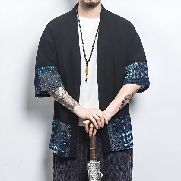 Homme portant un kimono noir avec motifs bleus et blancs aux manches et à l'ourlet. Vente de kimonos en ligne.