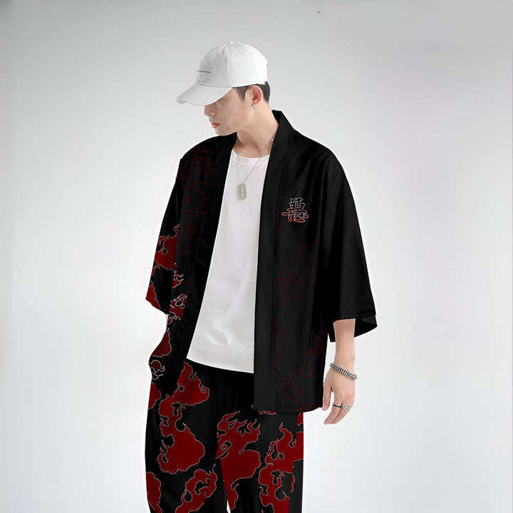 Homme portant un kimono noir avec motifs de flammes rouges et un kanji, associé à un pantalon assorti. Vêtement de style japonais, idéal pour un look unique et tendance. Découvrez notre collection de kimonos.