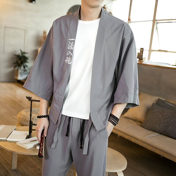 Homme portant un kimono gris avec motif calligraphique. Vêtements japonais traditionnels en vente.