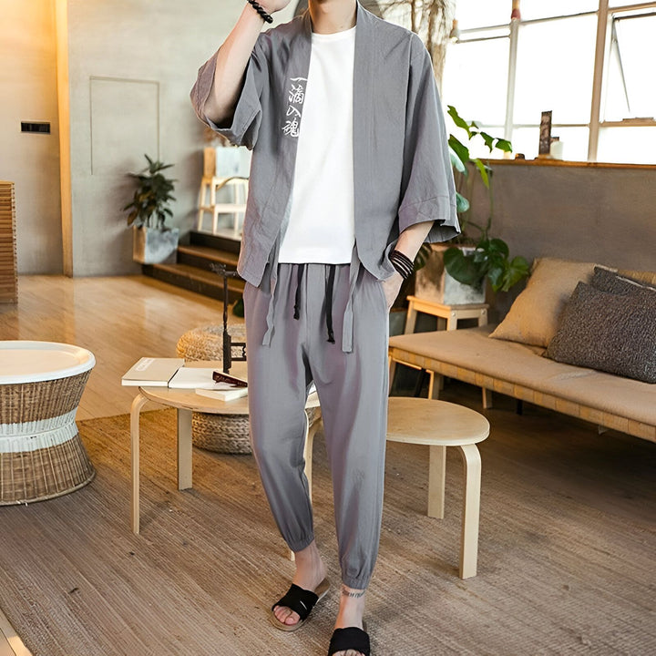 Homme portant un kimono gris avec un t-shirt blanc et un pantalon assorti. Vêtements de style japonais, disponibles à l'achat.
