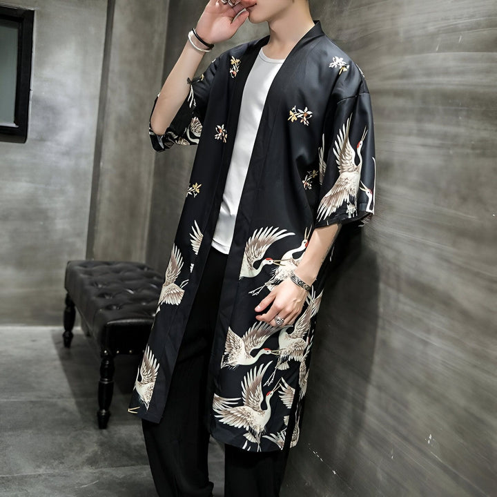 Homme portant un kimono noir avec motif de grues. Vêtement de style japonais, idéal pour un look tendance. Découvrez notre collection de kimonos uniques.