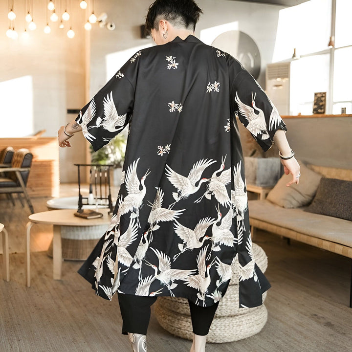 Homme portant un kimono noir long avec des motifs de grues blanches. Vêtement de style japonais.