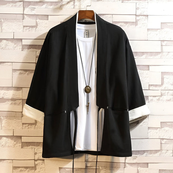 Kimono noir avec bordure blanche, porté sur un t-shirt blanc avec un collier. Vêtement traditionnel japonais, idéal pour un style unique. Découvrez notre collection de kimonos.