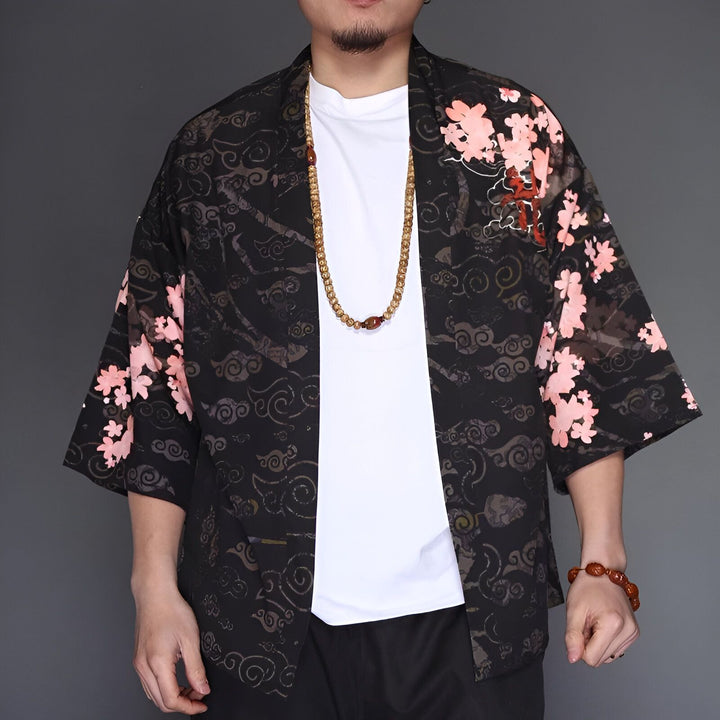 Homme portant un kimono noir à motifs floraux roses. Vêtement japonais traditionnel, parfait pour un style unique et élégant. Découvrez notre collection de kimonos.