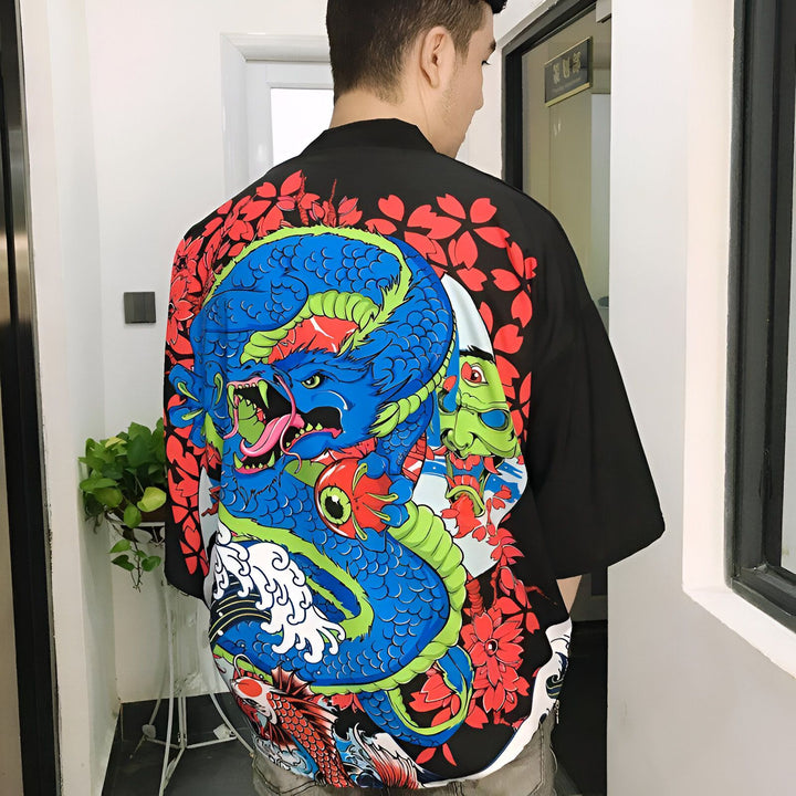 Homme portant un kimono noir avec un grand motif de dragon bleu, carpe koï et fleurs rouges. Vêtement de style japonais, idéal pour un look unique et tendance. Découvrez notre collection de kimonos authentiques.