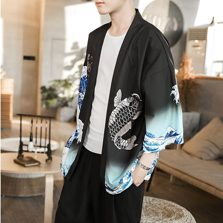 Homme portant un kimono noir avec des motifs de carpes koï blanches et d'ondes bleues. Vêtement de style japonais, idéal pour un look décontracté et tendance.