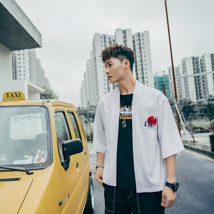 Homme portant un kimono blanc brodé avec taxi jaune en arrière-plan. Vêtements de style japonais à vendre.