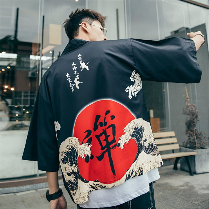 Homme portant un kimono noir avec un motif de soleil rouge, des vagues japonaises et des calligraphies. Vêtement traditionnel japonais à la mode. Notre collection de kimonos uniques.