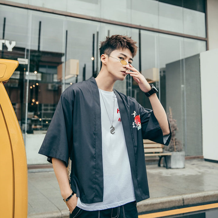 Homme portant un kimono noir moderne avec un t-shirt blanc et des lunettes de soleil jaunes. Vente de kimonos pour hommes et femmes.