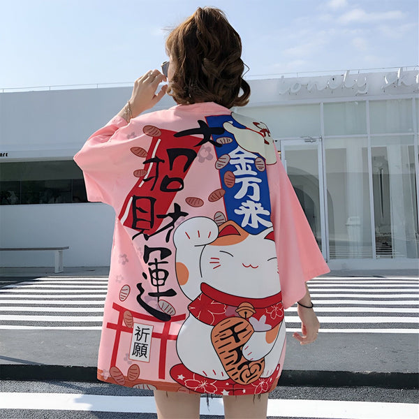 Femme vue de dos portant un kimono rose avec un motif de chat porte-bonheur japonais (Maneki Neko) et des kanjis. Vêtements de style japonais. Kimonos en vente.