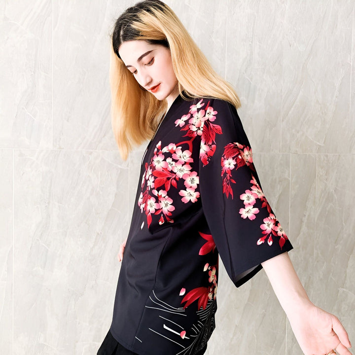 Femme portant un kimono noir à motifs floraux rouges et roses. Kimono traditionnel japonais à fleurs de cerisier. Vêtement de style asiatique. Produit kimono en vente.