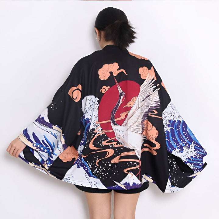Dos d'une personne portant un kimono noir orné d'une grue blanche, de vagues bleues et d'un soleil rouge. Vêtements de style japonais.