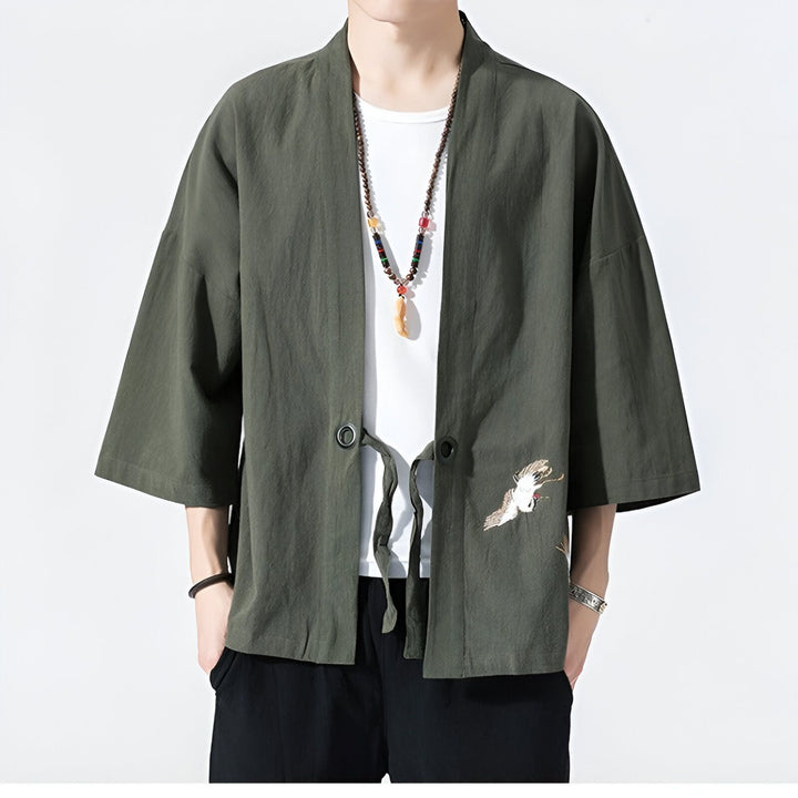 Homme portant un kimono vert olive avec une broderie de grue blanche. Vêtements de style japonais. Boutique de kimonos.