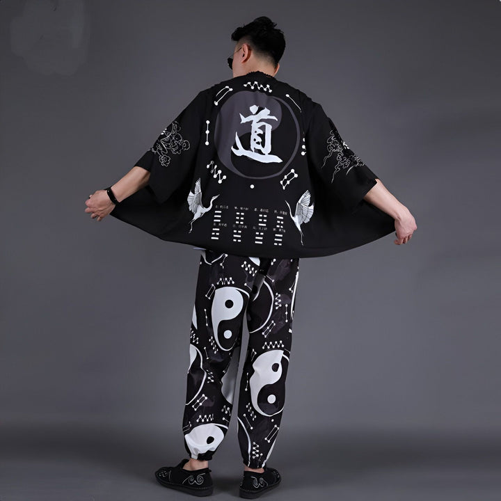 Homme portant un kimono noir avec motifs Yin Yang et grues blanches, assorti à un pantalon. Vêtements de style japonais à vendre.