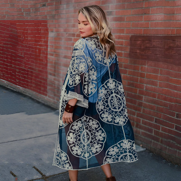 Femme portant un kimono bleu transparent à motifs floraux, idéale pour un look bohème chic. Découvrez notre collection de kimonos uniques et élégants.