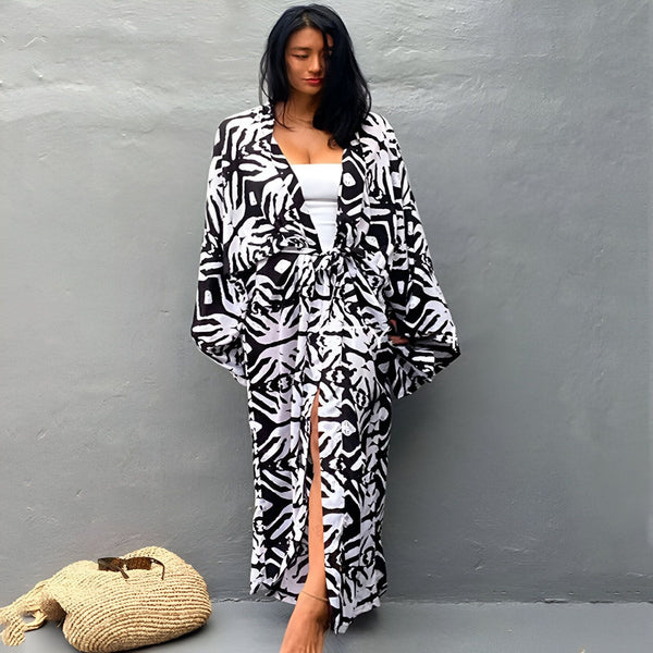 Femme portant un kimono long à motifs noir et blanc. Vêtement d'intérieur ou de plage élégant. Kimonos disponibles dans notre boutique.