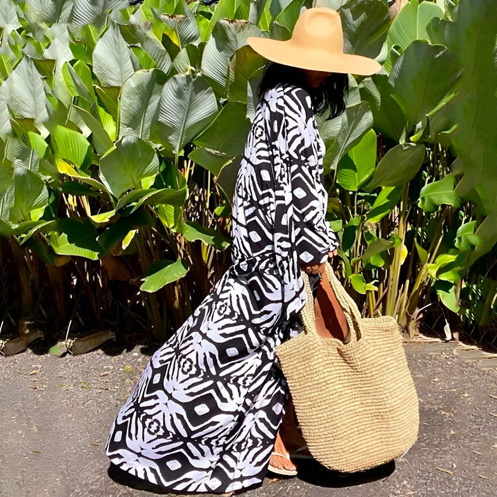 Femme portant un kimono à motifs noir et blanc, chapeau de paille et sac de plage. Kimonos élégants pour toutes les occasions.
