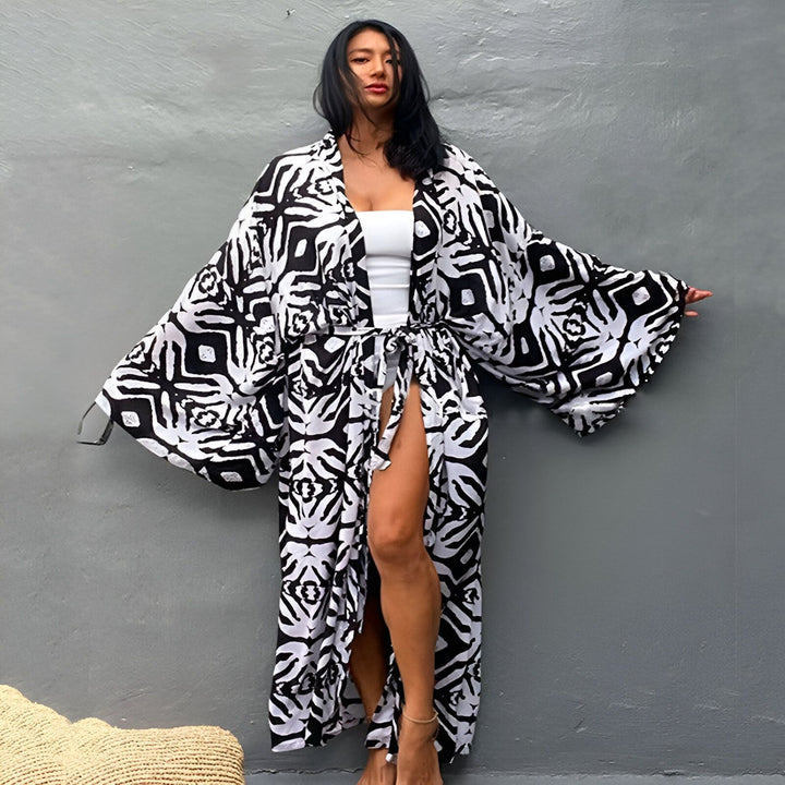 Femme portant un kimono long à motifs noir et blanc. Kimono de plage tendance, idéal pour l'été. Découvrez notre collection de kimonos uniques.