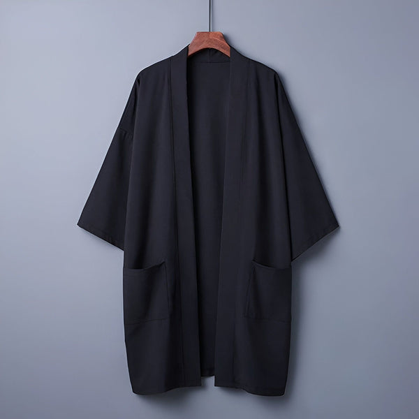 Kimono noir pour homme suspendu sur un cintre. Vêtement traditionnel japonais avec poches. Idéal pour un style décontracté ou élégant. Découvrez notre collection de kimonos uniques.