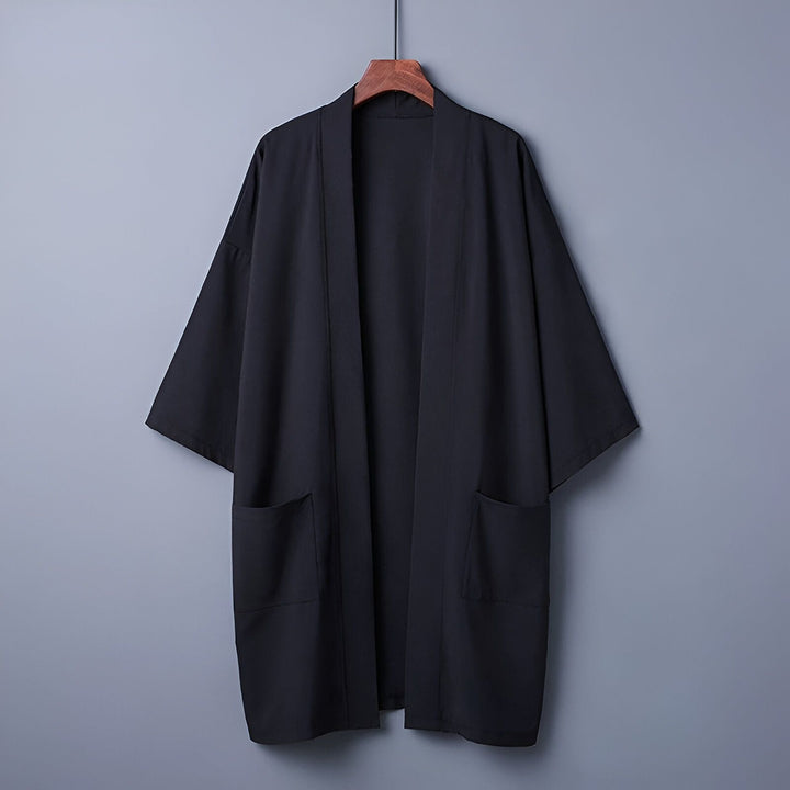 Kimono noir pour homme suspendu sur un cintre. Vêtement traditionnel japonais avec poches. Idéal pour un style décontracté ou élégant. Découvrez notre collection de kimonos uniques.