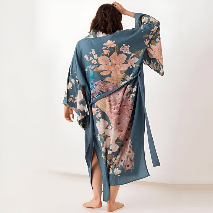 Femme vue de dos portant un kimono bleu imprimé avec des motifs floraux et un paon. Kimonos de haute qualité disponibles à l'achat.