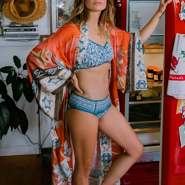 Femme portant un kimono fleuri coloré devant un frigo rouge. Lingerie assortie. Collection de kimonos floraux. Vêtements de détente confortables. Boutique de kimonos en ligne. Tendances mode kimono.