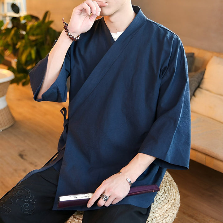 Homme portant un kimono bleu marine. Kimono traditionnel japonais, vêtement ample et confortable, parfait pour se détendre. Découvrez notre collection de kimonos en ligne.