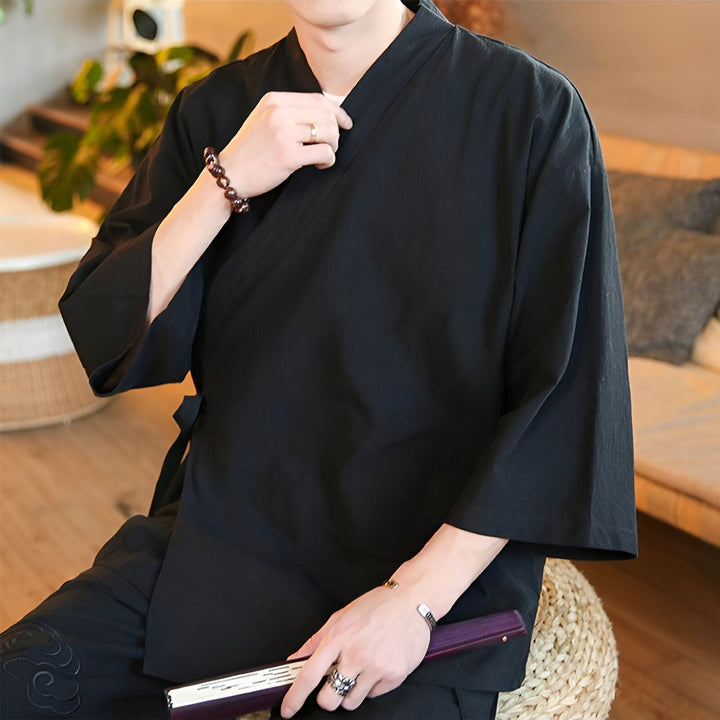 Homme portant un kimono noir traditionnel, vêtement japonais. Idéal pour un style décontracté et élégant. Découvrez notre collection de kimonos pour hommes.