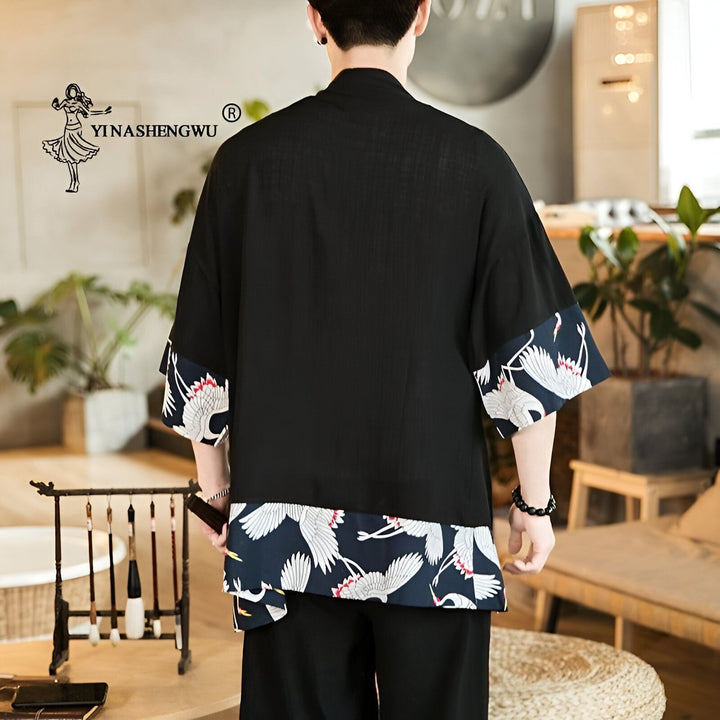 Homme portant un kimono noir avec motifs de grues blanches sur les manches et le bas. Vêtement japonais traditionnel. Boutique de kimonos. Style japonais moderne.