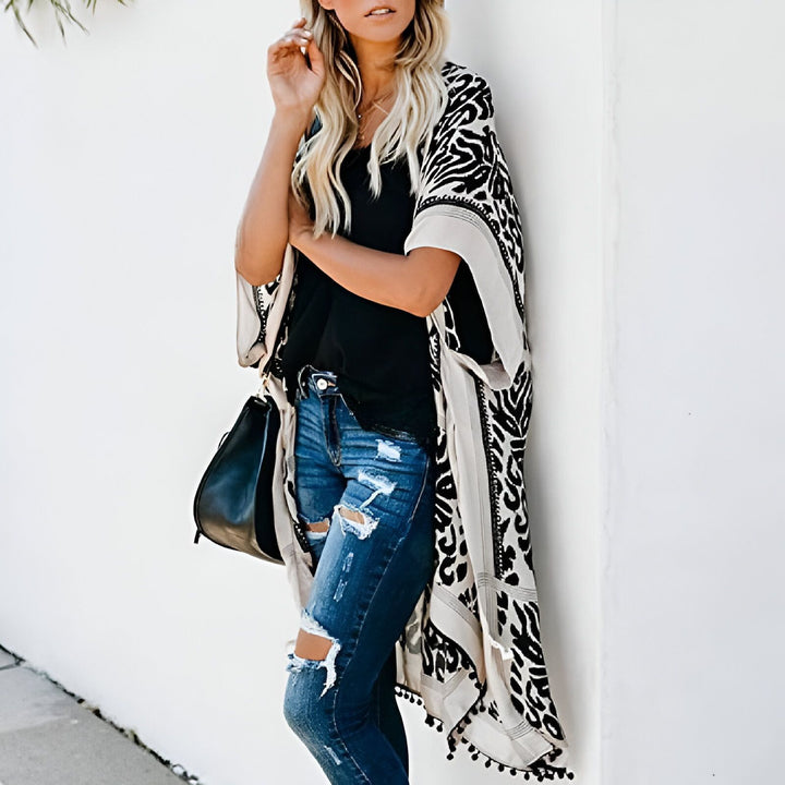 Femme portant un kimono à motifs noir et blanc, avec un jean déchiré et un sac noir. Vêtements de style kimono pour femmes. Boutique de kimonos en ligne. Nouveau modèle de kimono tendance.