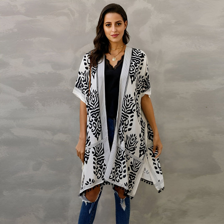 Femme portant un kimono blanc à motifs noirs. Vêtements de plage élégants. Kimono bohème pour femme, parfait pour l'été. Notre collection de kimonos est idéale pour toutes les occasions.