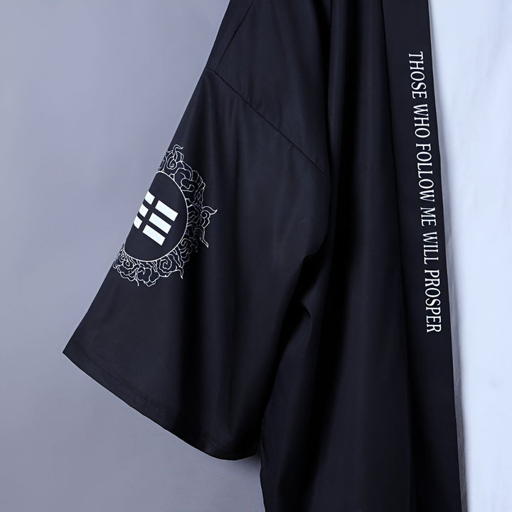 Détail d'un kimono noir avec motifs japonais sur la manche et inscription verticale. Kimonos à motifs disponibles dans notre boutique.