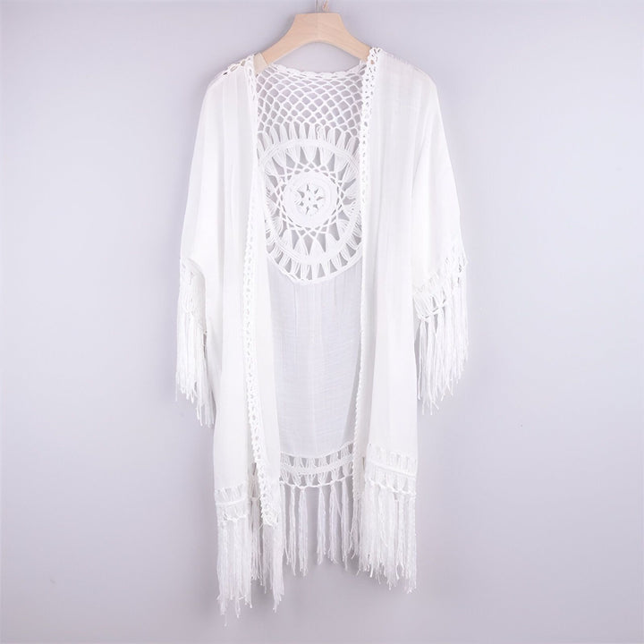 Kimono blanc à franges, avec un motif crocheté au dos, suspendu à un cintre. Vêtement léger et aéré parfait pour l'été. Boutique de kimonos.