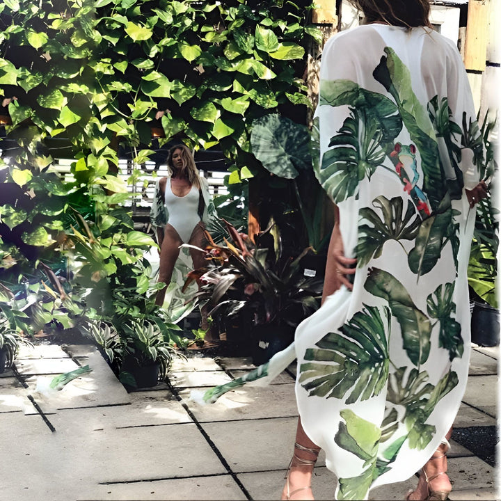 Deux femmes portant des kimonos légers à motifs de feuilles tropicales dans un jardin luxuriant. Kimonos parfaits pour l'été, disponibles dans notre boutique.