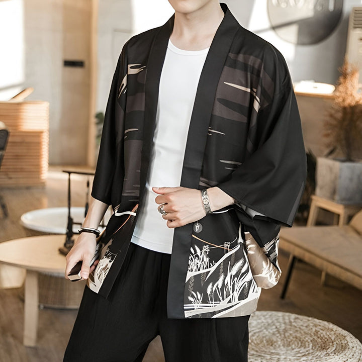 Homme portant un kimono noir imprimé, style japonais moderne. Vêtements traditionnels revisités, kimono pour homme de notre collection. Idéal pour un look décontracté et élégant. Découvrez nos kimonos uniques.
