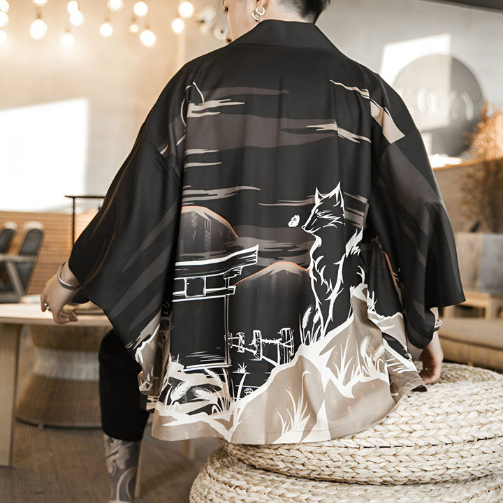 Dos d'une personne portant un kimono noir avec un motif de renard blanc et un paysage de style japonais. Vêtements traditionnels, vente de kimonos en ligne.