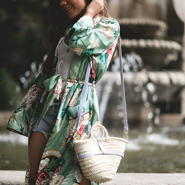 Femme souriante portant un kimono fleuri vert avec un sac en paille. Kimonos tendance pour femmes disponibles à l'achat.