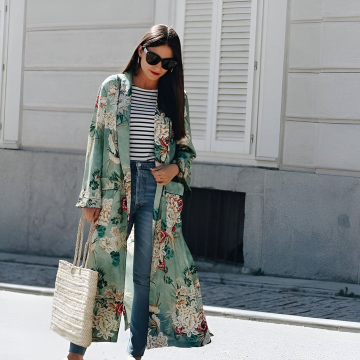 Femme portant un kimono long à motifs floraux, associé à un jean et un haut rayé. Look tendance et décontracté. Collection de kimonos pour femme.