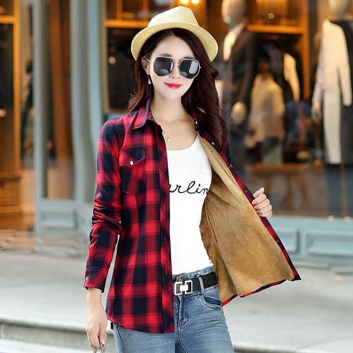 Femme portant une chemise à carreaux rouge et noir ouverte, doublée de fourrure, avec un chapeau et des lunettes de soleil. Style décontracté, vêtement d'extérieur confortable. Kimono revisité pour un look moderne.