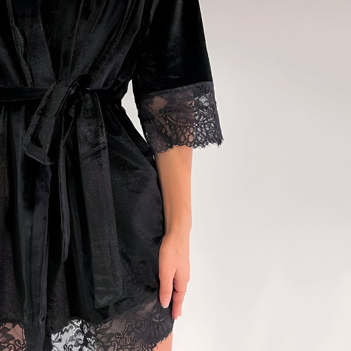 Kimono noir en velours avec bordure en dentelle. Détail de la ceinture et des manches. Vêtement de détente élégant.