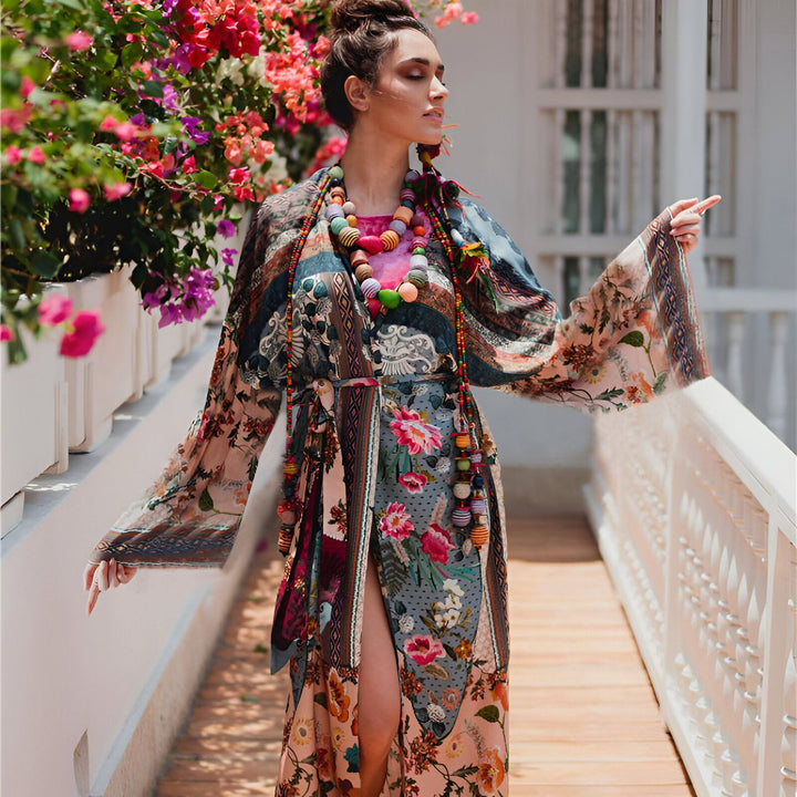 Femme portant un kimono fleuri coloré, avec un collier à grosses perles. Kimono long et fluide, idéal pour un look bohème chic. Découvrez notre collection de kimonos uniques.