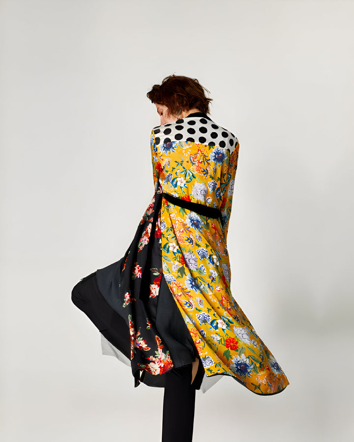 Femme portant un kimono long et coloré. Motifs floraux jaune et détails à pois. Ceinture noire à la taille. Vêtement de style japonais, disponible à l'achat.