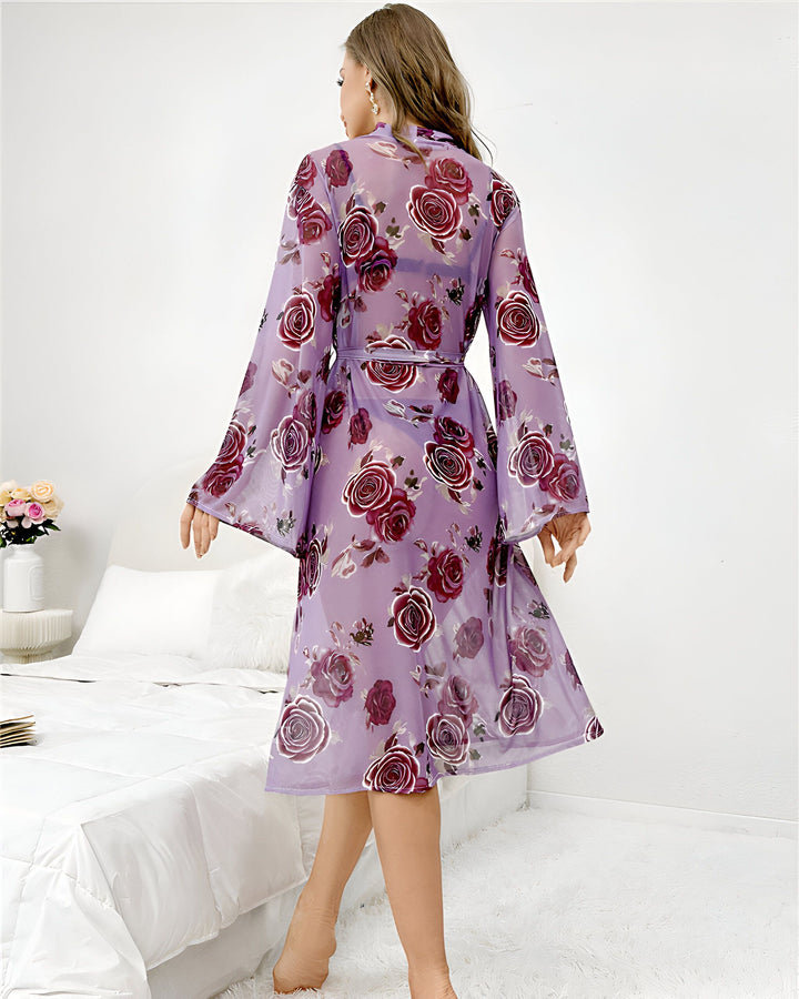 Kimono violet transparent à motifs floraux roses, manches amples, ceinture assortie. Vêtement léger et élégant, idéal pour la détente ou comme tenue d'intérieur. Disponible dans notre collection de kimonos.