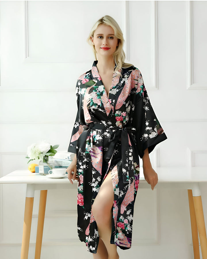 Femme blonde portant un kimono noir à motifs floraux et de paon, noué à la taille. Vente de kimonos élégants et confortables.