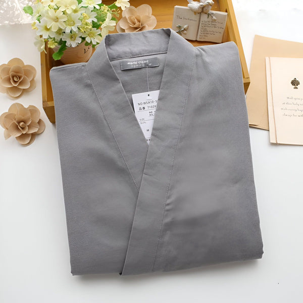 Kimono gris Marie Claire plié sur une table avec décorations florales et cartes. Vêtement traditionnel japonais à découvrir dans notre boutique.