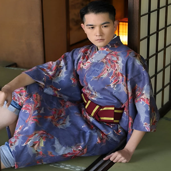 Homme en kimono bleu à motifs floraux rouges, assis sur un tatami. Ceinture obi bordeaux et or. Vêtements traditionnels japonais. Kimonos de qualité à vendre en ligne.