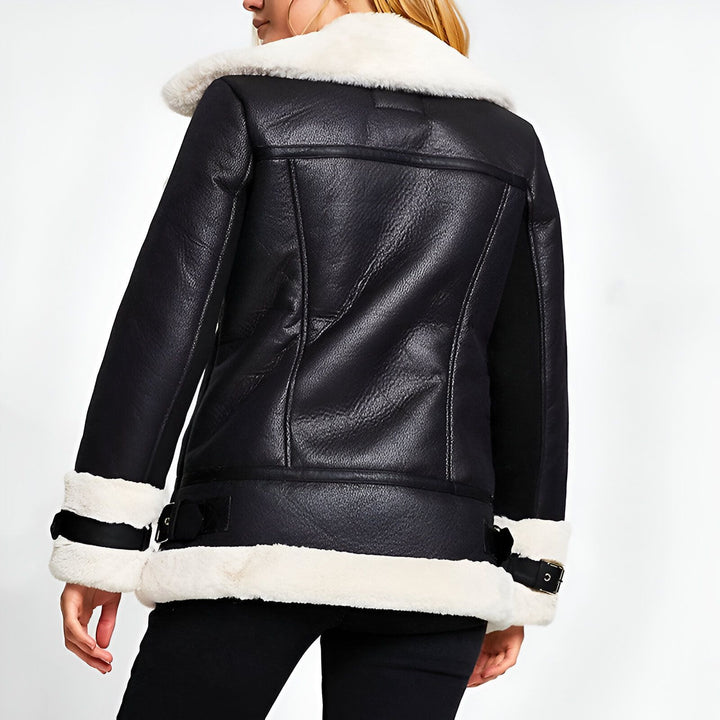 Veste aviateur noire en similicuir avec col en fausse fourrure blanche. Détails de boucles et ceinture. Idéale pour un look tendance et chaud.