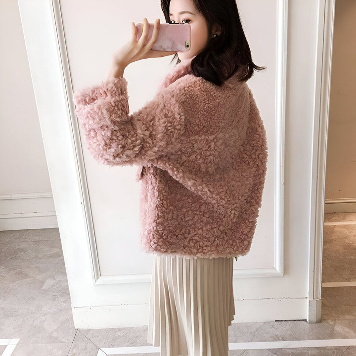 Femme portant un manteau rose duveteux et une jupe plissée claire. Vêtements d'hiver tendance. Collection de kimonos.