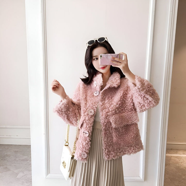 Femme prenant un selfie avec un manteau en fausse fourrure rose, chemisier blanc et jupe plissée. Sac à main blanc avec chaîne dorée. Mode hivernale. Vêtements de dessus élégants.