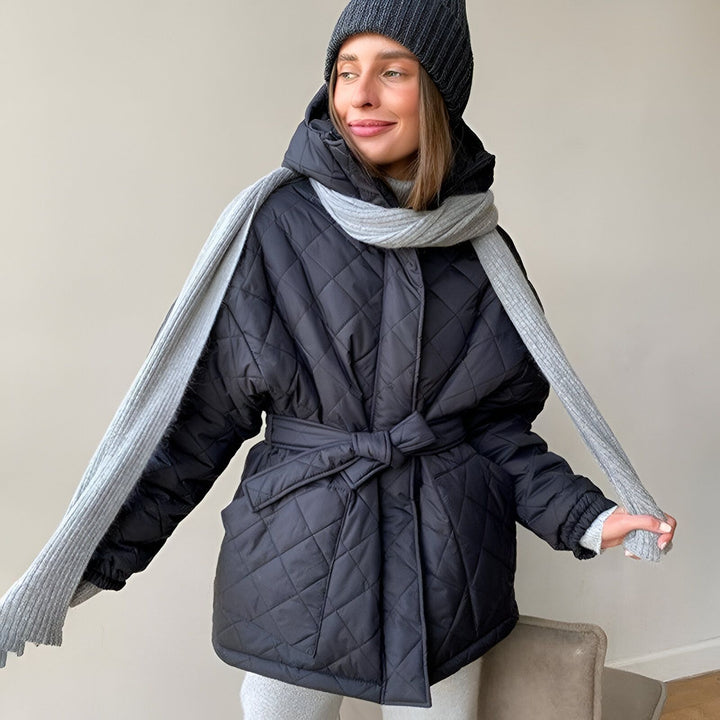Femme portant un kimono matelassé noir avec une ceinture nouée, un bonnet et une écharpe gris. Vêtements d'hiver confortables et élégants.